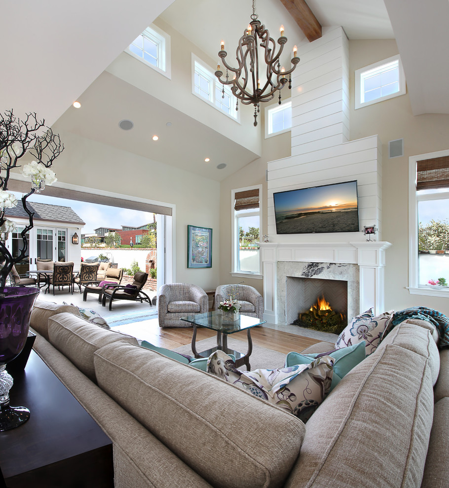Mittelgroßes Maritimes Wohnzimmer mit beiger Wandfarbe, hellem Holzboden und Kaminumrandung aus Stein in Orange County