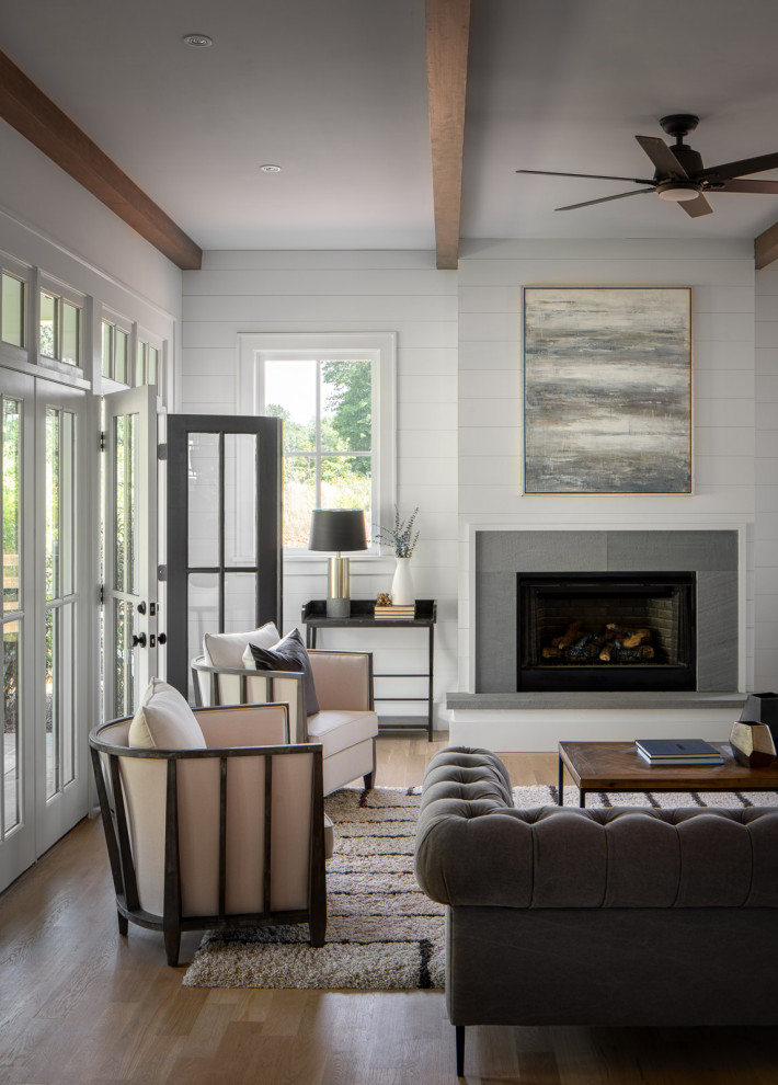 Landhaus Wohnzimmer mit weißer Wandfarbe, braunem Holzboden, Kamin und braunem Boden in Atlanta