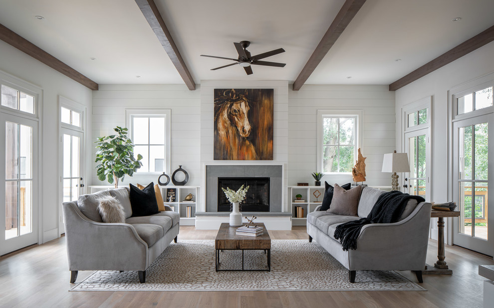 Landhaus Wohnzimmer mit weißer Wandfarbe, braunem Holzboden, Kamin, gefliester Kaminumrandung und braunem Boden in Atlanta