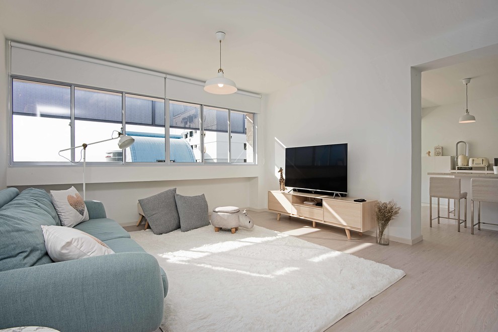 Foto på ett minimalistiskt allrum med öppen planlösning, med vita väggar, ljust trägolv, en fristående TV och beiget golv