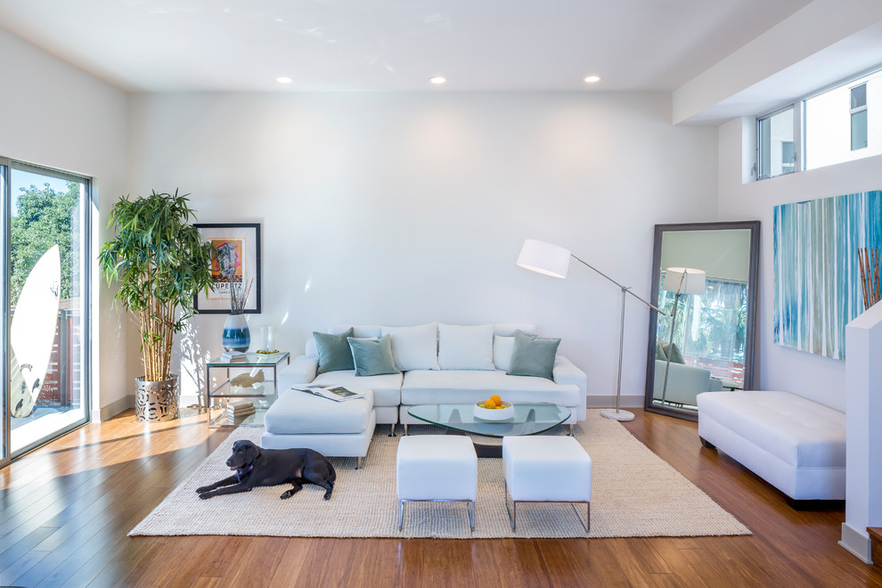 Cette image montre un salon design ouvert avec un mur blanc, un sol en bois brun et un sol marron.