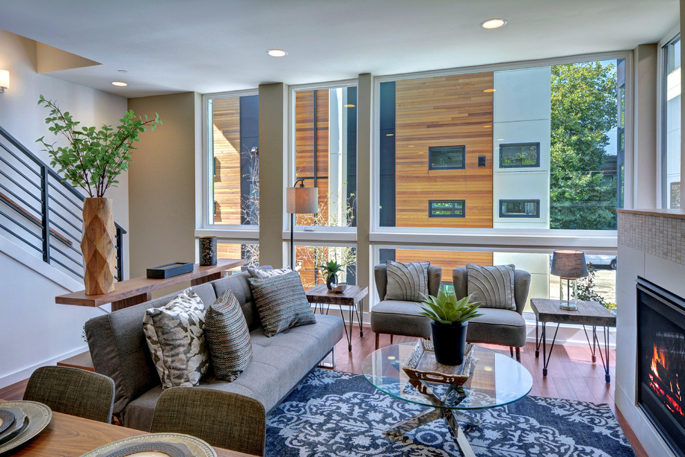Kleines, Offenes Modernes Wohnzimmer mit grauer Wandfarbe, braunem Holzboden, Kamin und gefliester Kaminumrandung in Seattle