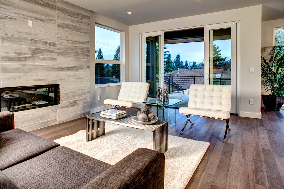 Example of a mid-sized trendy open concept medium tone wood floor living room design in Seattle with gray walls, a ribbon fireplace, a tile fireplace and a wall-mounted tv