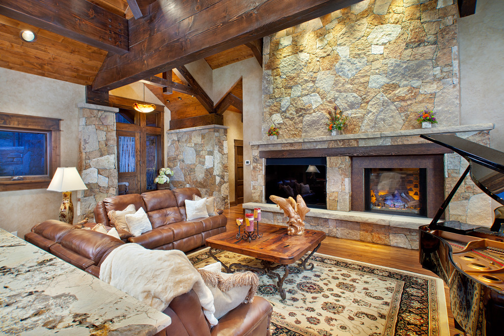 Klassisches Wohnzimmer mit beiger Wandfarbe, Kamin, Kaminumrandung aus Stein und Steinwänden in Denver