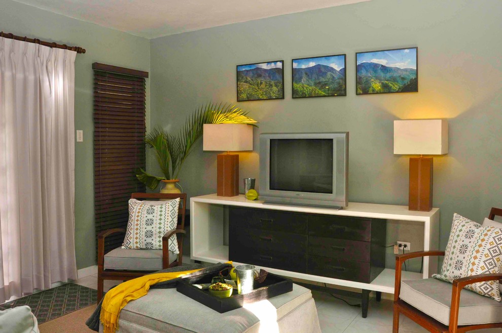 Immagine di un piccolo soggiorno tropicale con TV autoportante e pavimento beige