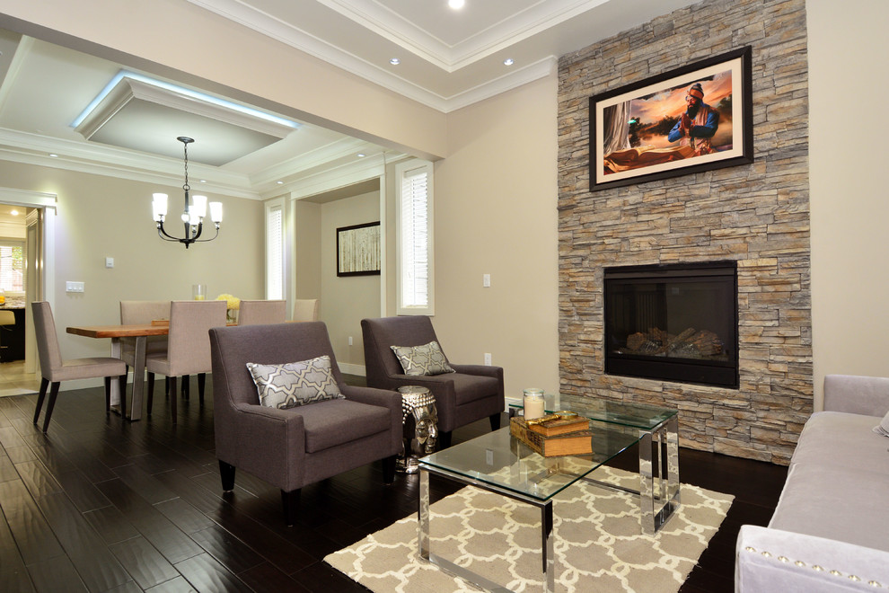 This is an example of a classic formal open plan living room in Vancouver with grey walls, medium hardwood flooring, a hanging fireplace, a stone fireplace surround and no tv.