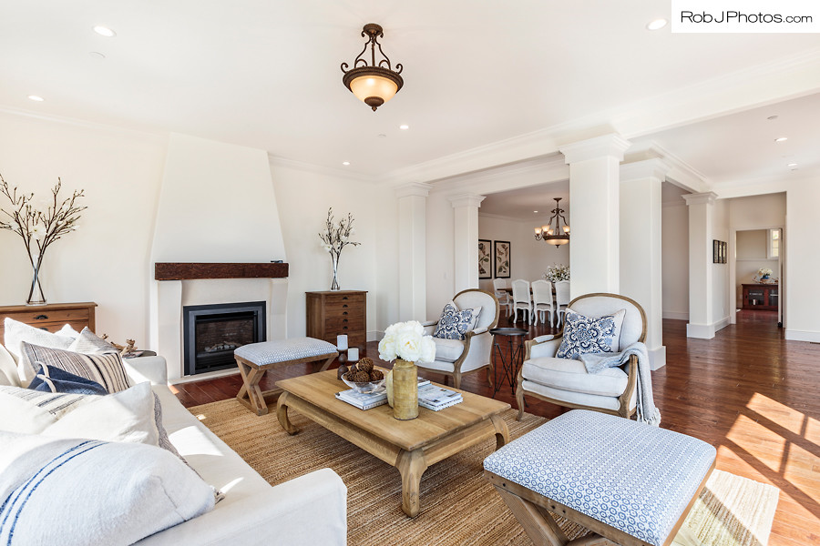 Cette photo montre un grand salon méditerranéen ouvert avec un mur blanc, un sol en bois brun et une cheminée standard.