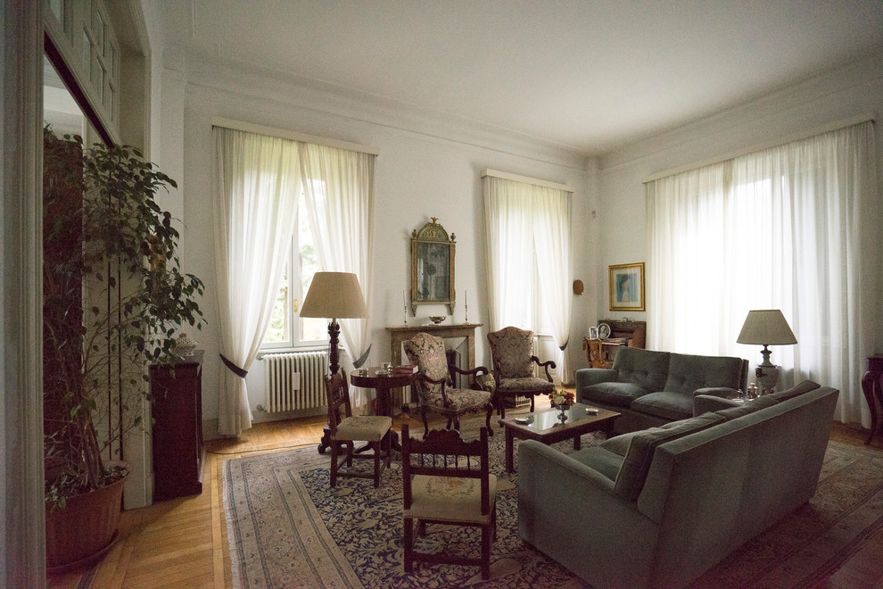 Immagine di un ampio soggiorno chic chiuso con sala formale, pareti bianche, parquet chiaro, camino classico e cornice del camino in metallo