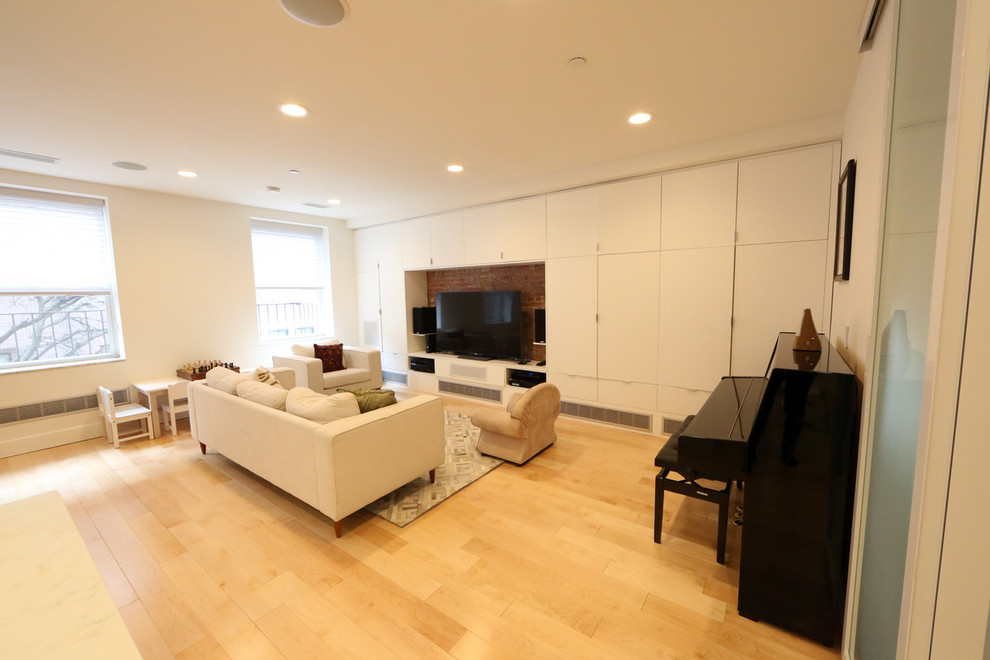 Large contemporary open plan living room in New York with a music area, white walls, light hardwood flooring, no fireplace and a freestanding tv.
