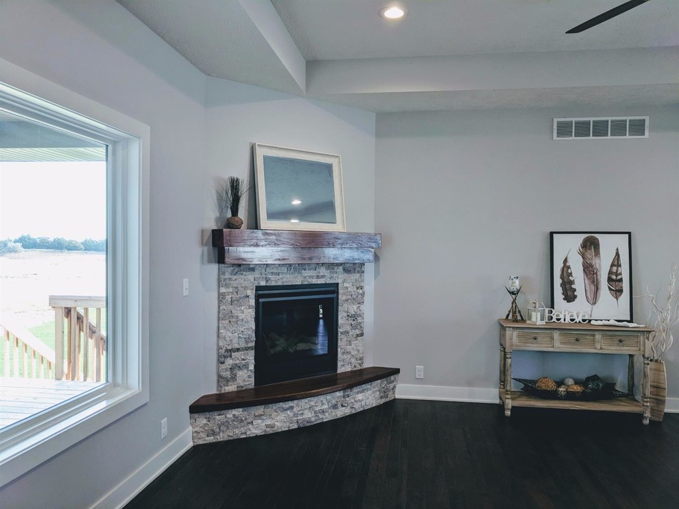オマハにある低価格の小さなトラディショナルスタイルのおしゃれなリビング (グレーの壁、コーナー設置型暖炉、石材の暖炉まわり、茶色い床) の写真