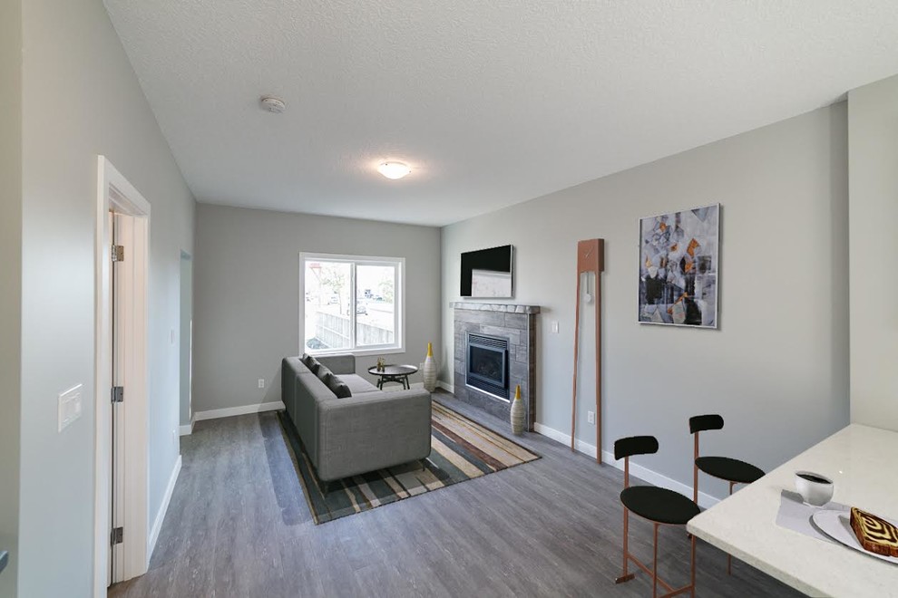 Mittelgroßes, Offenes Klassisches Wohnzimmer mit grauer Wandfarbe, Vinylboden, Kamin, gefliester Kaminumrandung und TV-Wand in Edmonton