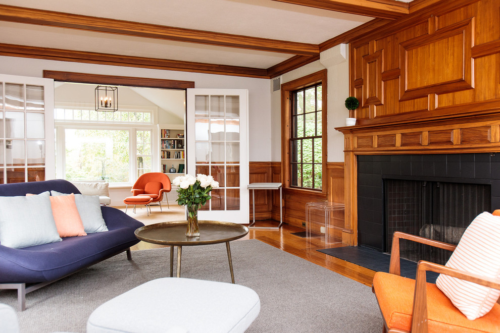 Cette photo montre un grand salon chic fermé avec un sol en bois brun, une cheminée standard, un manteau de cheminée en carrelage et un sol gris.