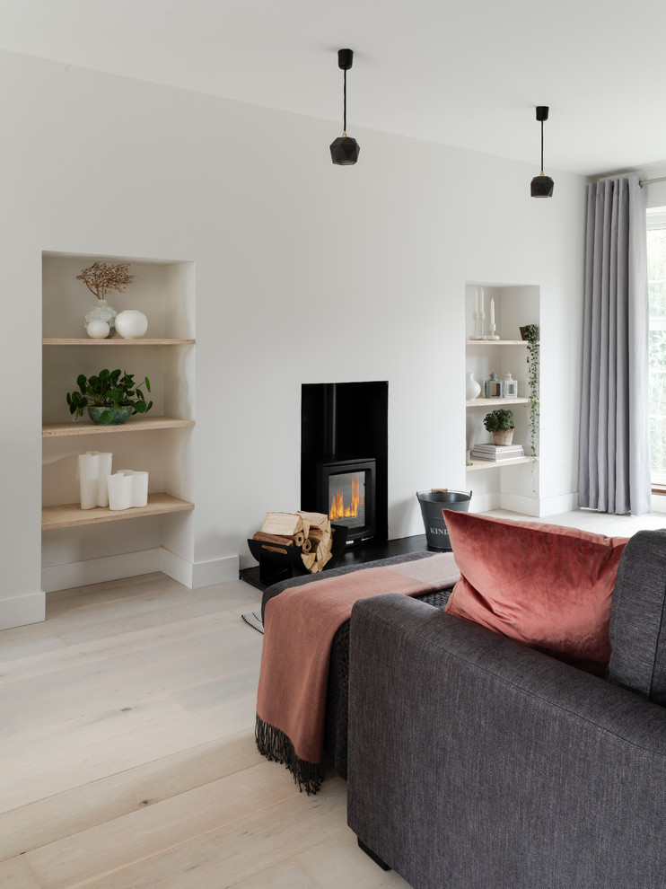 Imagen de salón abierto actual pequeño con paredes blancas, suelo de madera clara, estufa de leña y suelo blanco