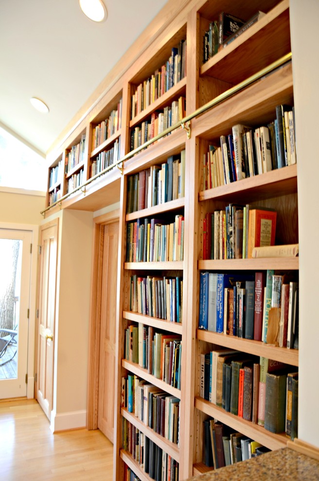 Modelo de biblioteca en casa cerrada tradicional grande con paredes beige, suelo de madera clara y pared multimedia