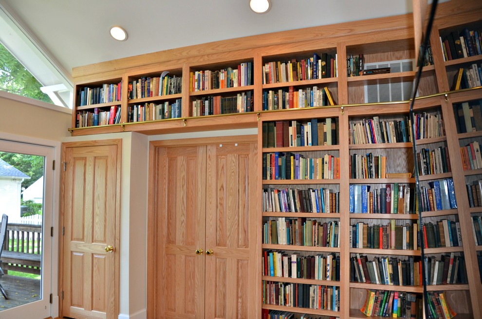 Ispirazione per un soggiorno chic di medie dimensioni e chiuso con libreria, pareti beige, parquet chiaro e parete attrezzata