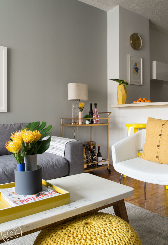 Immagine di un soggiorno moderno di medie dimensioni e aperto con pareti grigie, pavimento in legno massello medio e TV a parete