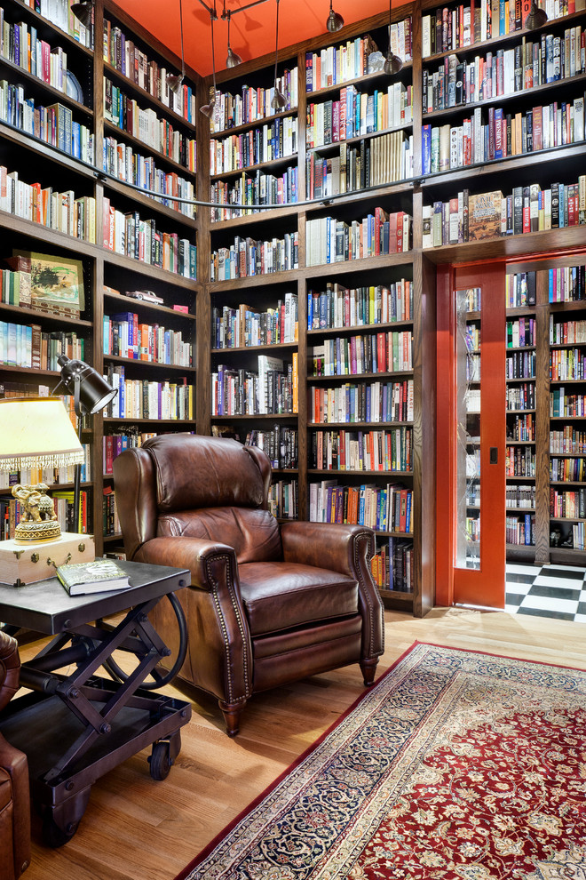 Immagine di un soggiorno minimal con libreria, pareti rosse e parquet chiaro