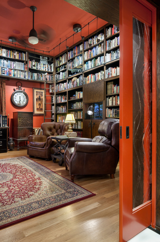 Ispirazione per un soggiorno design chiuso con libreria, pareti rosse e parquet chiaro