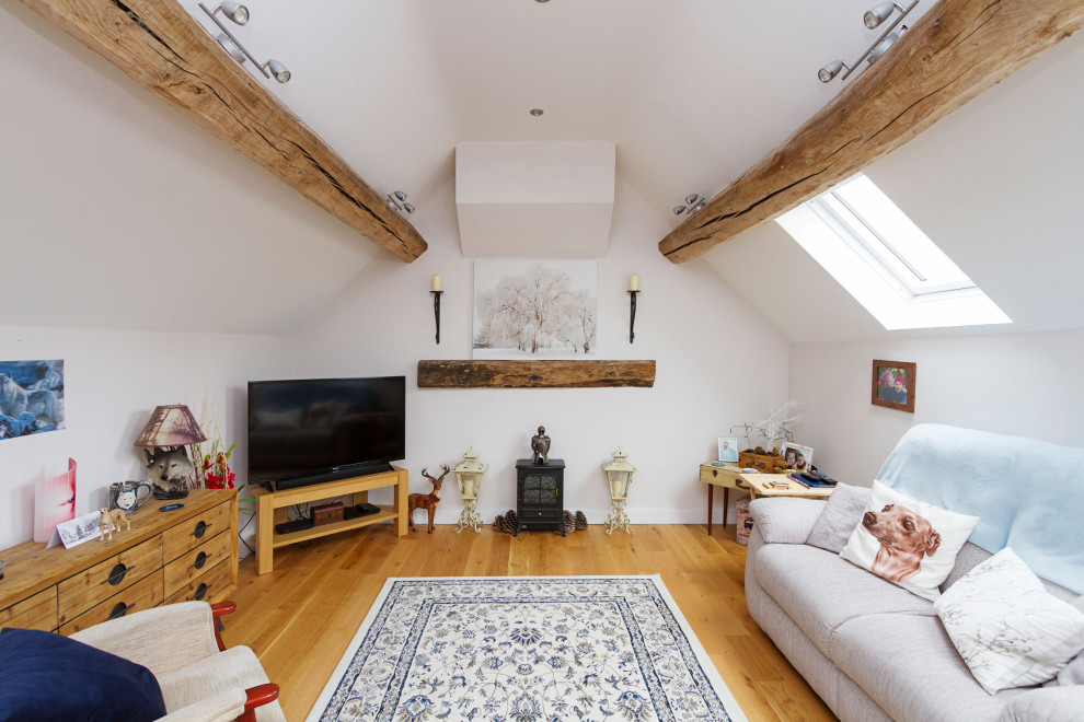 Kleines, Repräsentatives, Offenes Uriges Wohnzimmer mit lila Wandfarbe, hellem Holzboden, Kaminofen, freistehendem TV, beigem Boden und freigelegten Dachbalken in West Midlands