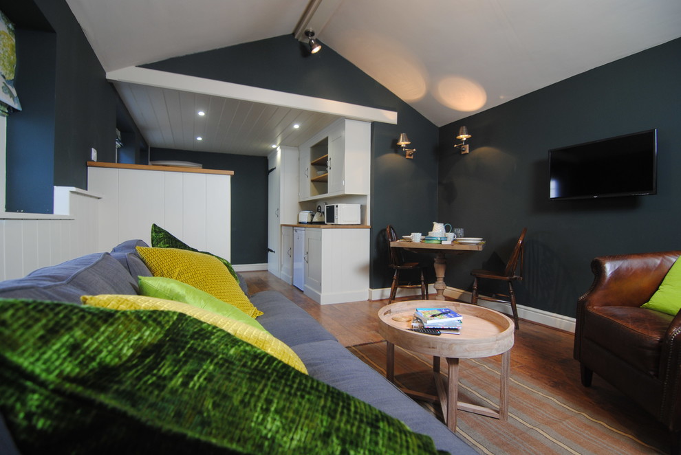 Inspiration för små eklektiska vardagsrum, med en väggmonterad TV, gröna väggar, laminatgolv och brunt golv