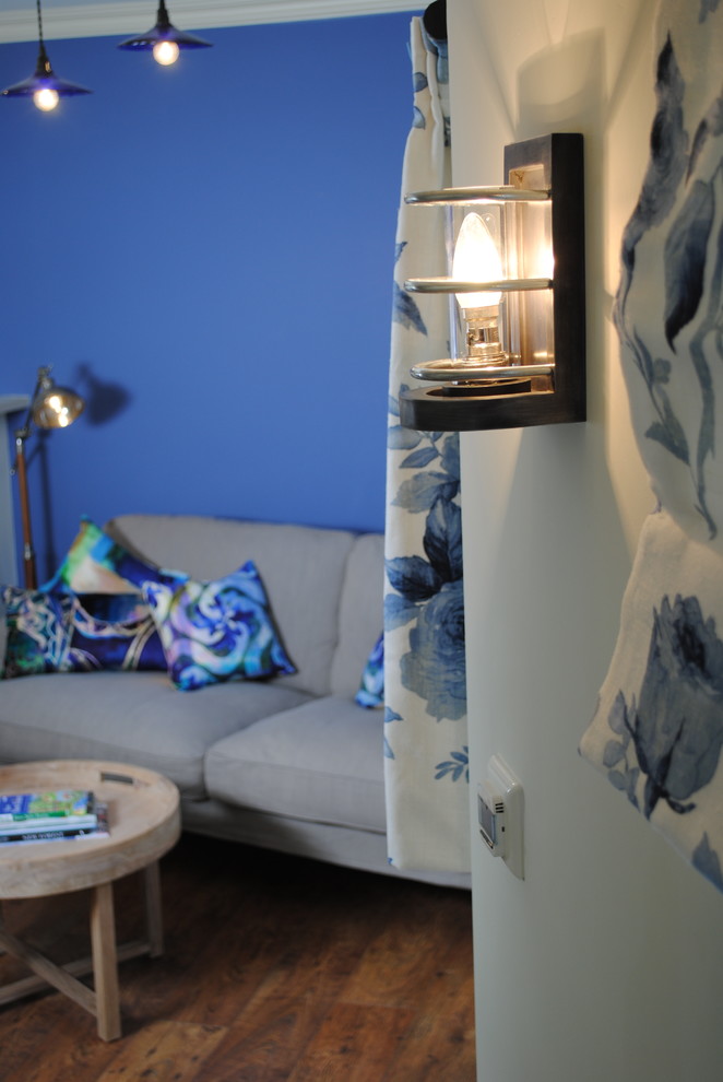 Foto de salón ecléctico pequeño con paredes azules, televisor colgado en la pared y suelo laminado