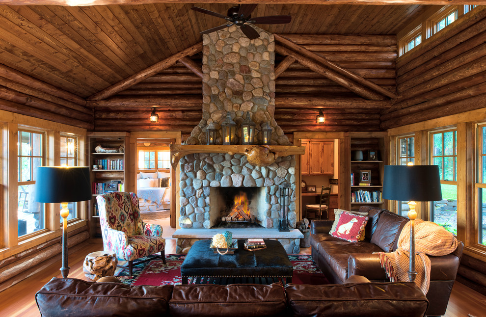 This is an example of a medium sized rustic open plan living room in Minneapolis with a reading nook, brown walls, a standard fireplace, a stone fireplace surround, brown floors and medium hardwood flooring.