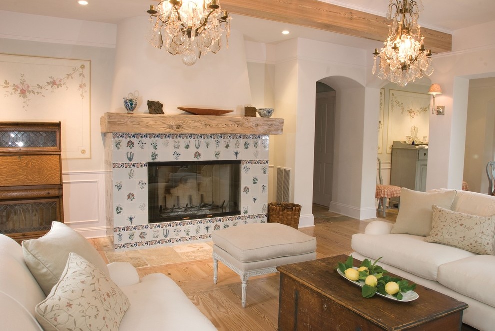На фото: гостиная комната в стиле кантри с бежевыми стенами, паркетным полом среднего тона, стандартным камином и фасадом камина из плитки