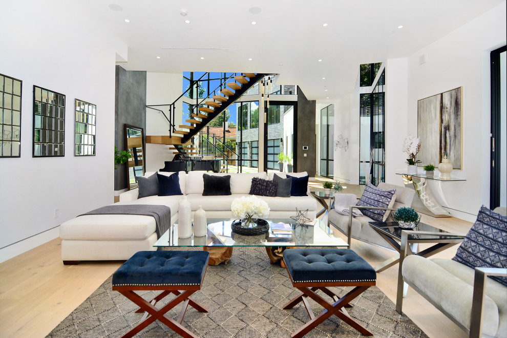 Example of a huge trendy open concept light wood floor living room design in Los Angeles with white walls, a two-sided fireplace and a stone fireplace
