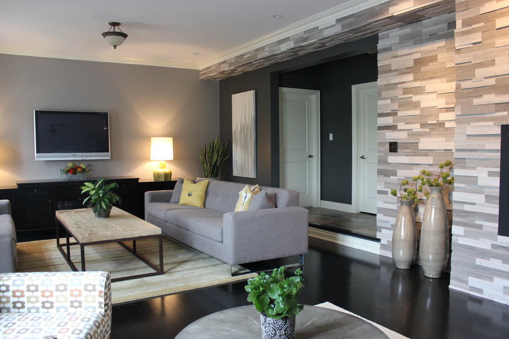 Пример оригинального дизайна: большая открытая гостиная комната в стиле неоклассика (современная классика) с серыми стенами, полом из керамогранита, стандартным камином, фасадом камина из камня, телевизором на стене и черным полом