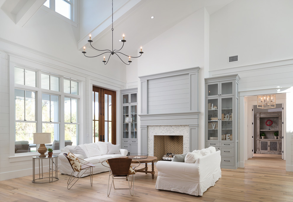 На фото: большая открытая гостиная комната:: освещение в стиле неоклассика (современная классика) с белыми стенами, стандартным камином и фасадом камина из плитки