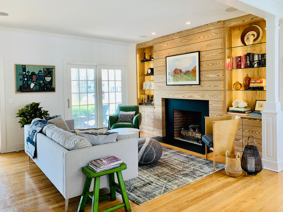 Immagine di un soggiorno design aperto con pareti bianche, pavimento in legno massello medio, camino classico, pavimento marrone e pareti in legno