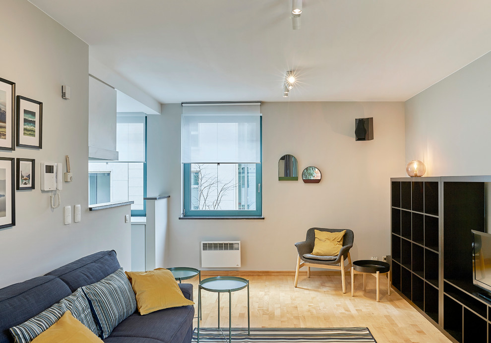 Idee per un soggiorno minimal con pareti grigie, TV autoportante e parquet chiaro