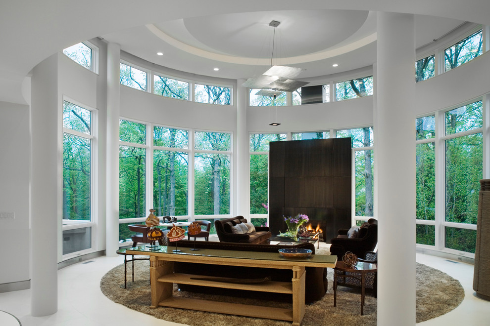 На фото: большая открытая гостиная комната в современном стиле с белыми стенами, полом из известняка, фасадом камина из металла, скрытым телевизором, стандартным камином, белым полом и сводчатым потолком