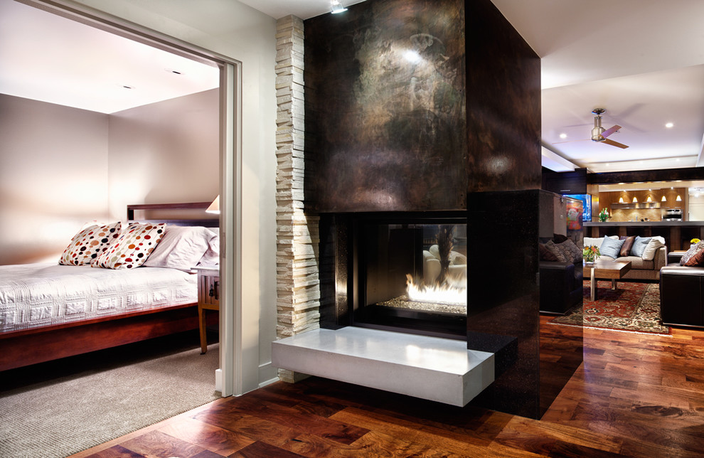Offenes Modernes Wohnzimmer mit braunem Holzboden, Tunnelkamin, Kaminumrandung aus Stein und TV-Wand in Austin