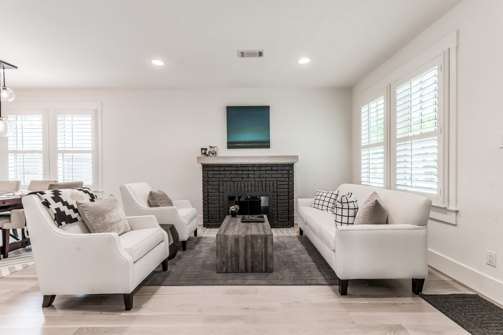 Photo of a medium sized country open plan living room in Houston with white walls, light hardwood flooring, a standard fireplace, a brick fireplace surround, a wall mounted tv and white floors.