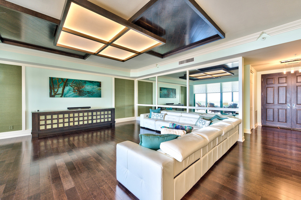 Offenes Modernes Wohnzimmer ohne Kamin mit beiger Wandfarbe, dunklem Holzboden und verstecktem TV in Miami