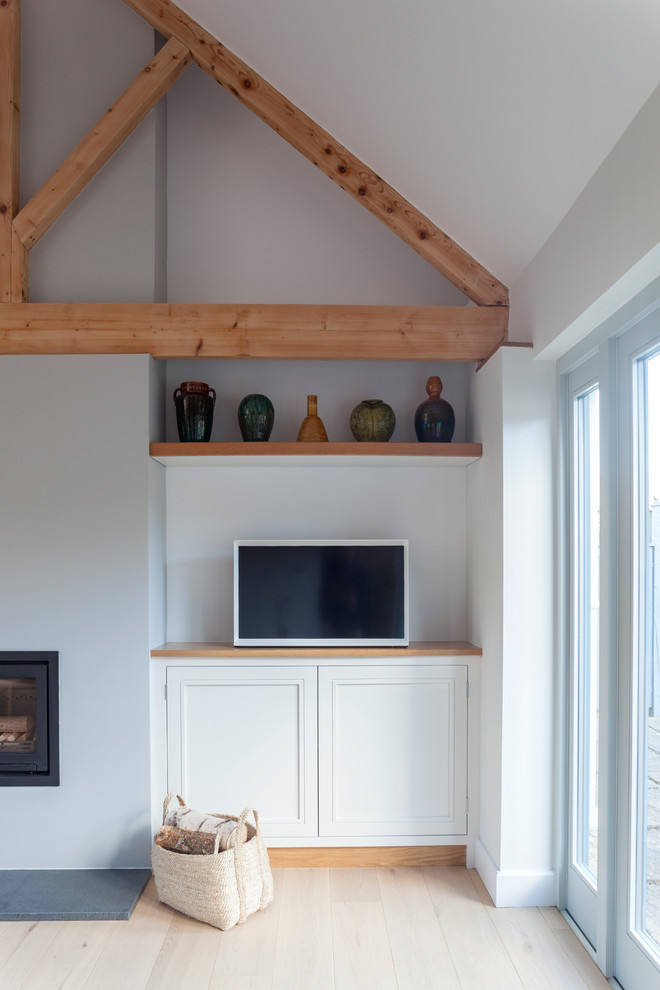 Esempio di un soggiorno design di medie dimensioni e chiuso con pareti bianche, pavimento in legno verniciato, stufa a legna, cornice del camino in mattoni, TV autoportante e pavimento beige