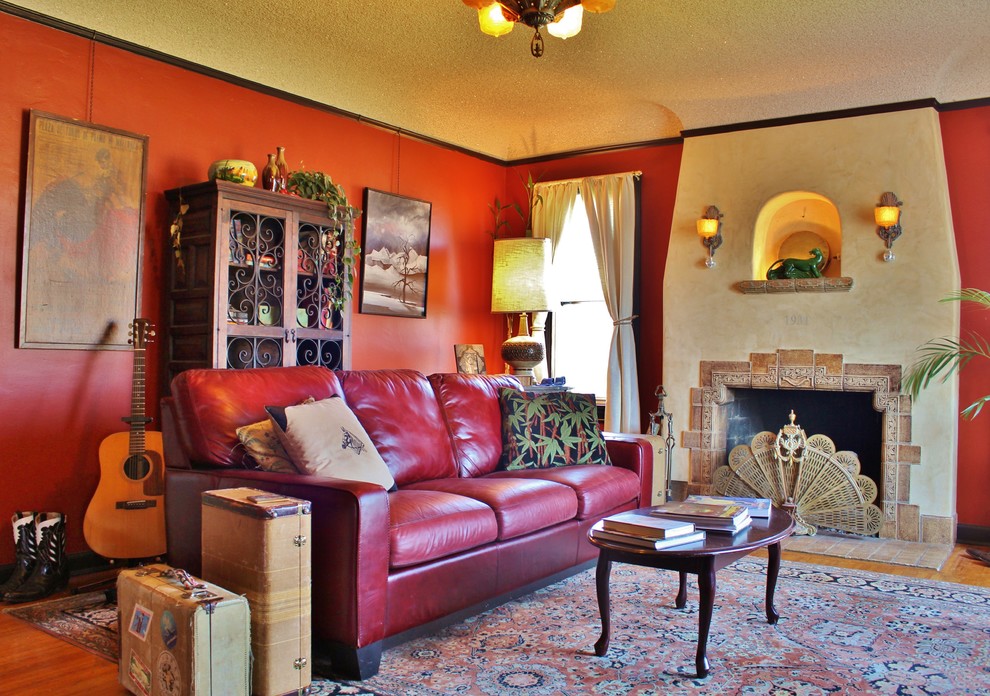 На фото: изолированная гостиная комната в стиле фьюжн с красными стенами, стандартным камином и фасадом камина из плитки с
