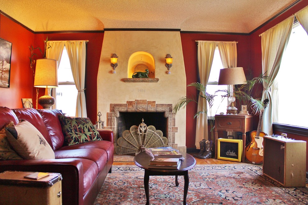 На фото: изолированная, парадная гостиная комната в стиле фьюжн с красными стенами, стандартным камином, фасадом камина из плитки и паркетным полом среднего тона без телевизора