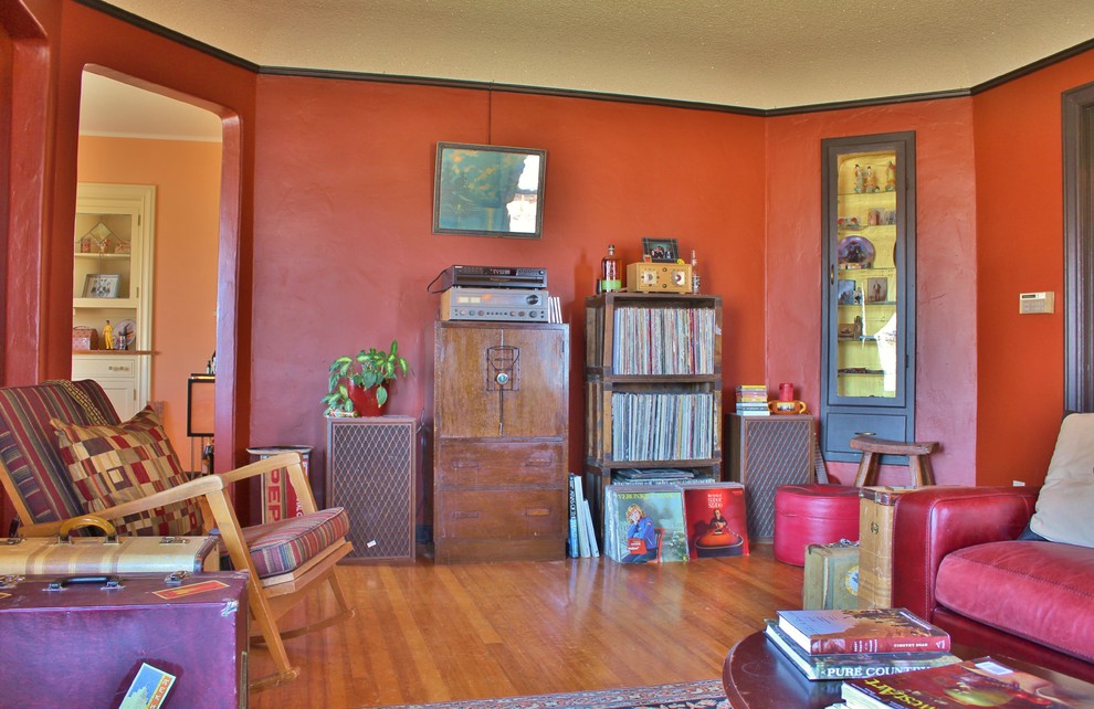 На фото: изолированная гостиная комната в стиле фьюжн с красными стенами, паркетным полом среднего тона, стандартным камином и фасадом камина из плитки с