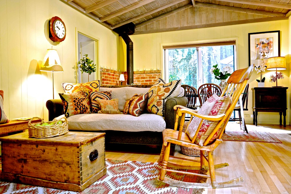 Foto de salón abierto romántico de tamaño medio con paredes beige, suelo de madera clara, estufa de leña y televisor retractable