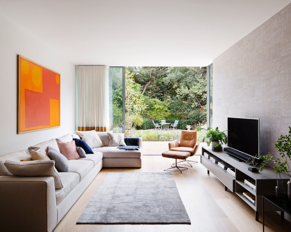 Modernes Wohnzimmer mit grauer Wandfarbe, hellem Holzboden, freistehendem TV, beigem Boden und Tapetenwänden in London