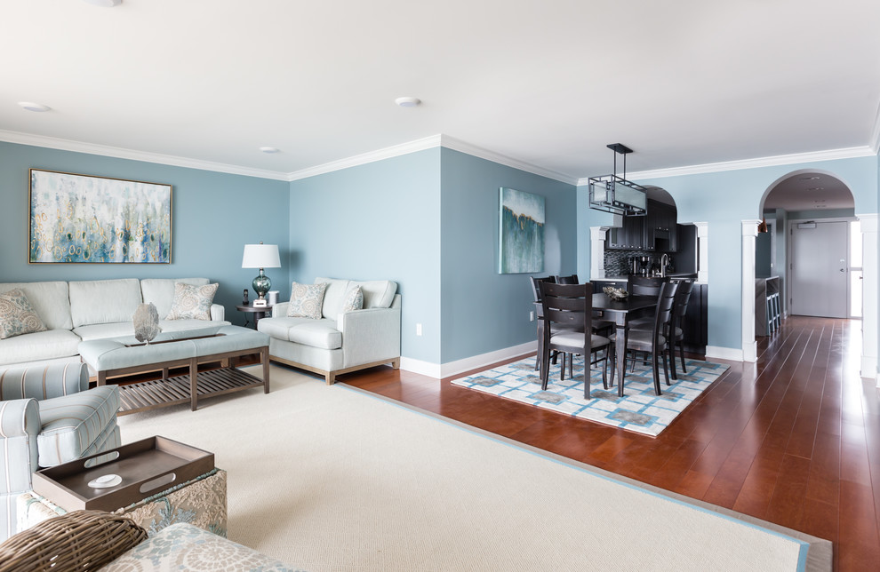 Diseño de salón abierto costero sin chimenea y televisor con paredes azules, suelo de madera en tonos medios y suelo marrón