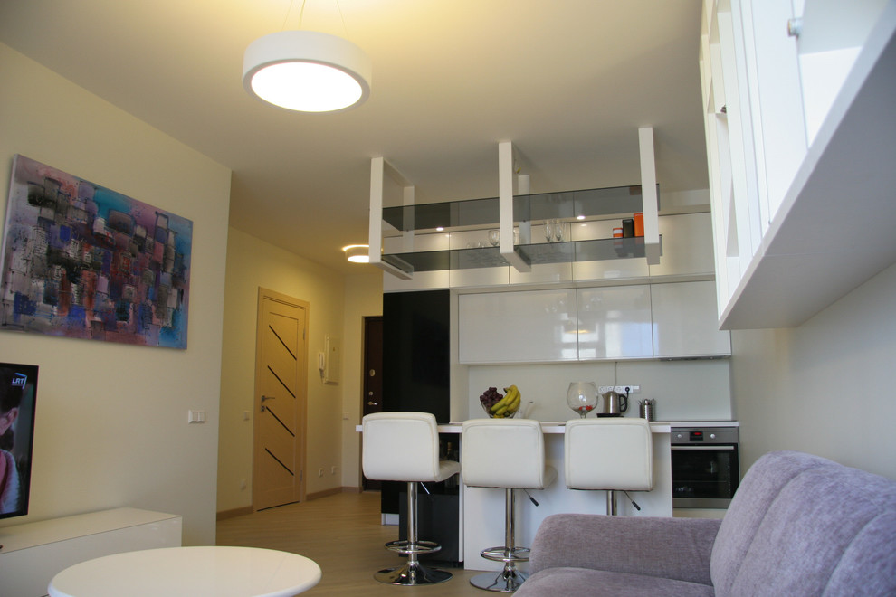На фото: маленькая открытая гостиная комната в стиле модернизм с домашним баром, белыми стенами, светлым паркетным полом и отдельно стоящим телевизором для на участке и в саду
