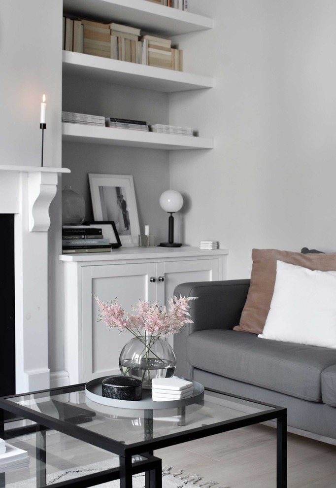 Inspiration for a medium sized scandi enclosed living room in Other with grey walls, light hardwood flooring, a standard fireplace, a wooden fireplace surround, a freestanding tv and beige floors.