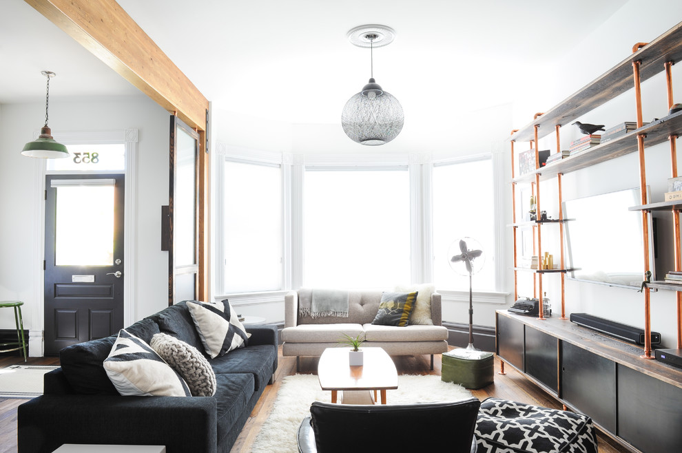 Diseño de salón abierto bohemio de tamaño medio con paredes blancas, suelo de madera en tonos medios y televisor colgado en la pared