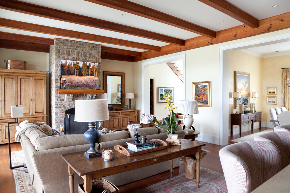 Ispirazione per un soggiorno con pareti beige, pavimento in legno massello medio, camino classico e cornice del camino in mattoni