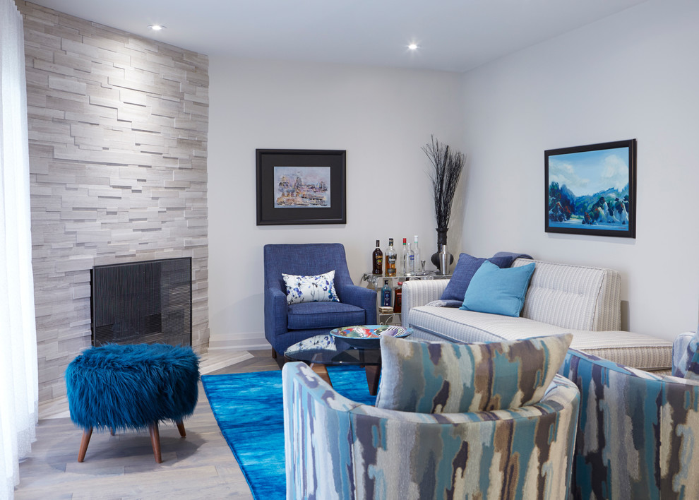 トロントにあるラグジュアリーな広いコンテンポラリースタイルのおしゃれなLDK (青い壁、無垢フローリング、コーナー設置型暖炉、石材の暖炉まわり、グレーの床) の写真