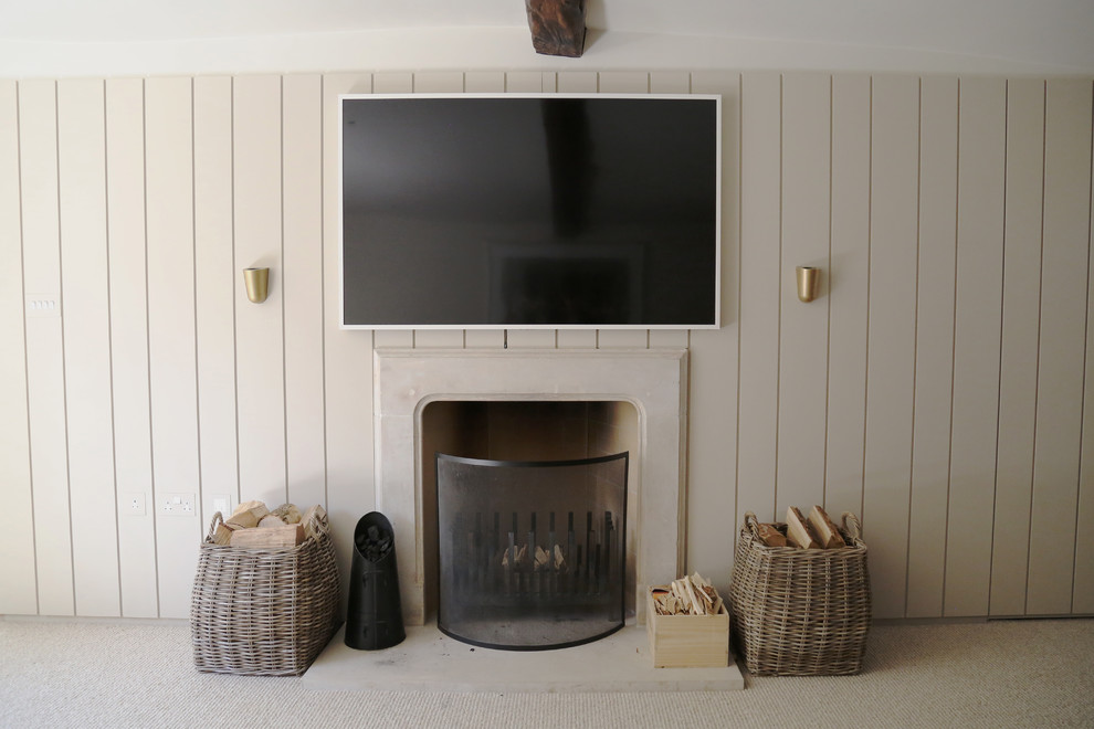 グロスタシャーにある高級な中くらいなコンテンポラリースタイルのおしゃれなLDK (ベージュの壁、カーペット敷き、標準型暖炉、石材の暖炉まわり、壁掛け型テレビ、ベージュの床) の写真