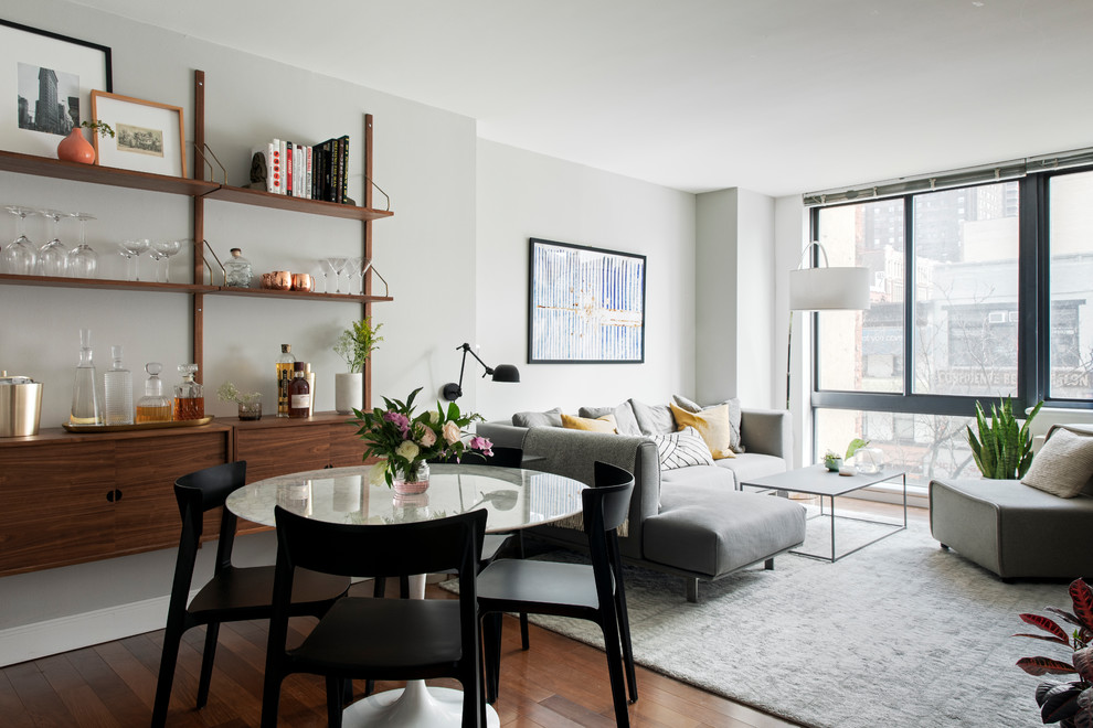 Mittelgroßes, Offenes Mid-Century Wohnzimmer ohne Kamin mit grauer Wandfarbe, hellem Holzboden, TV-Wand und braunem Boden in New York